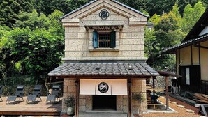 A traditional building with a tiled roof, a clock, and a sign with a logo. - Daigo-sauna (Daigo)