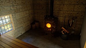 A room with a fireplace, a window, and a wooden bench. - Daigo-sauna (Daigo)