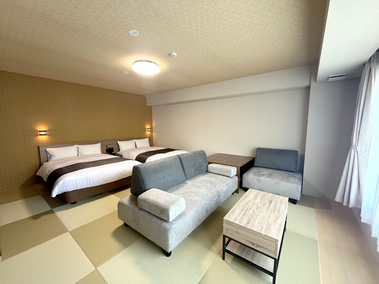 A hotel room with a bed, a sofa, a small table, and a chair.