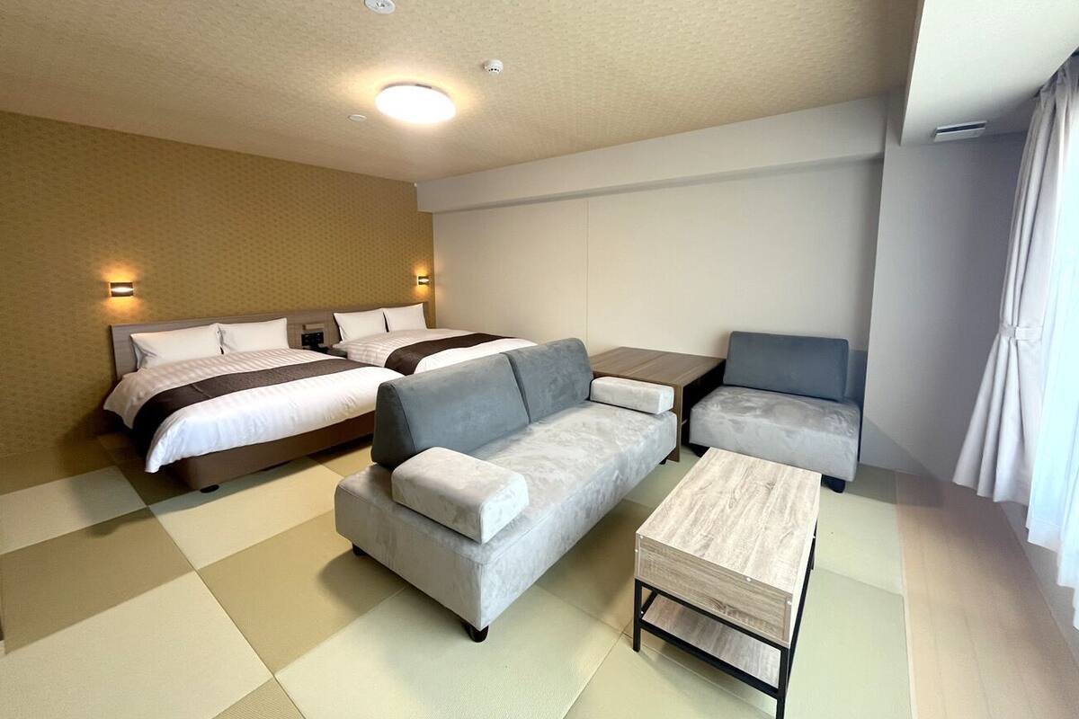 A hotel room with a bed, a sofa, a small table, and a chair.