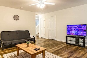 Ein Wohnzimmer mit einer schwarzen Couch, einem Holztisch und einem Fernseher auf einem schwarzen Schrank.