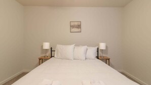Une chambre d’hôtel avec un grand lit, deux tables de chevet et un tableau encadré au mur.