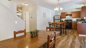Une cuisine moderne avec des meubles en bois, une table à manger avec des chaises et un lustre.