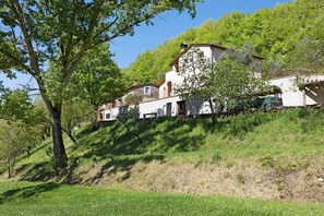 A hillside property with multiple buildings, including a large house with a balcony and a smaller structure. - Relaxing Double Room Surrounded by Nature (Vicchio)