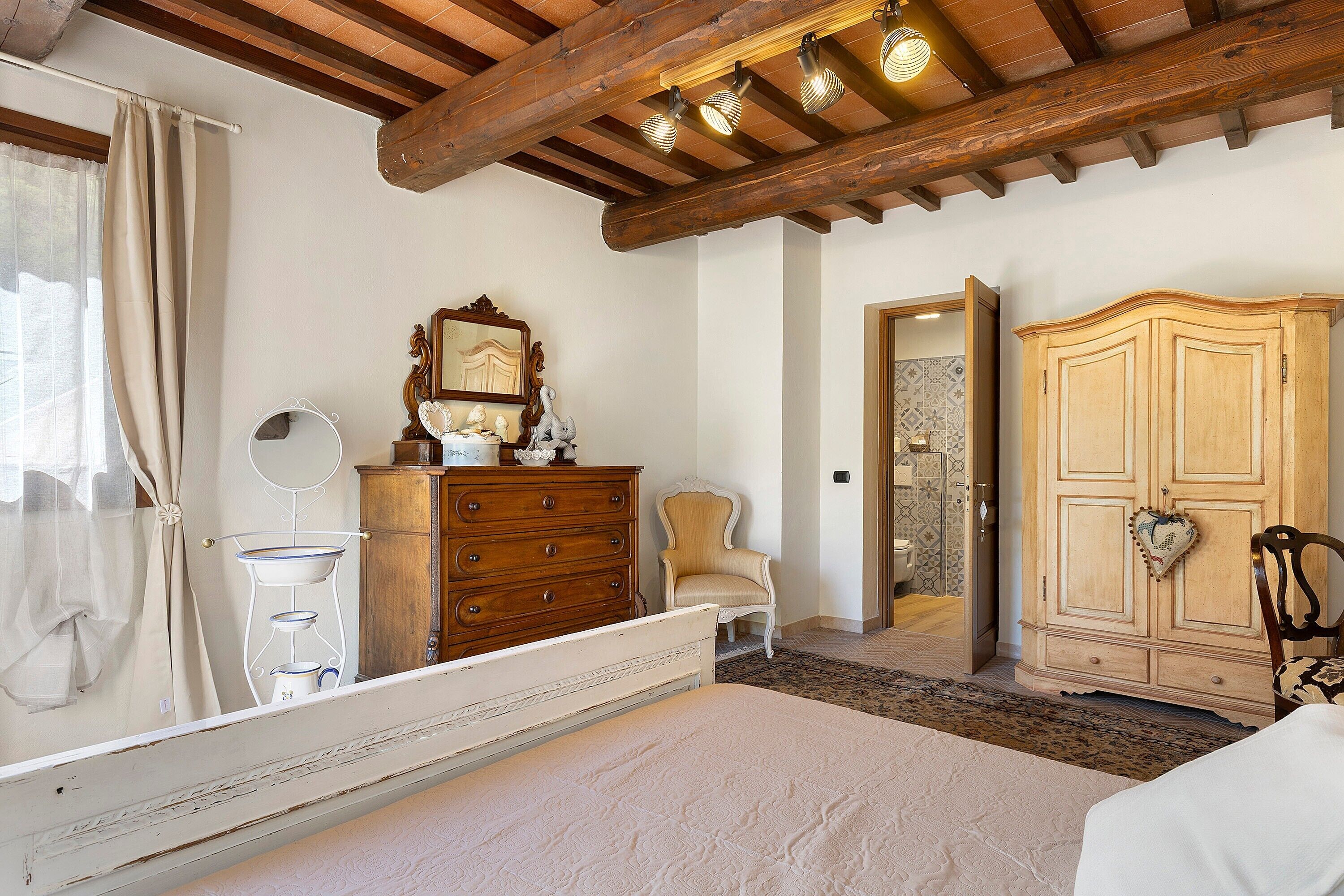 Une chambre à coucher avec un lit, une commode en bois, une chaise et un miroir.