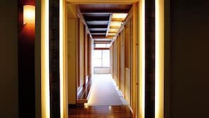 A narrow hallway with wooden flooring and walls, leading to a bright room with a large window. - Aizuyanaizu Onsen Seiryunoyado Kawachi (Yanaizu)