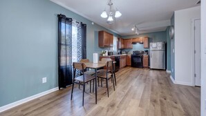 A modern kitchen with wooden cabinets, a dining table with chairs, and a refrigerator. - Pet-Friendly House Near Ft Benning w/ Free Parking (Columbus)
