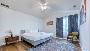 A bedroom with a bed, a nightstand, a chair, a ceiling fan, and a window with curtains. - Pet-Friendly House Near Ft Benning w/ Free Parking (Columbus)
