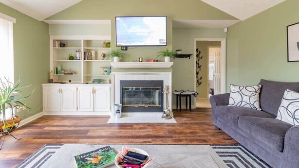Een woonkamer met een open haard, een televisie erboven en een bank.