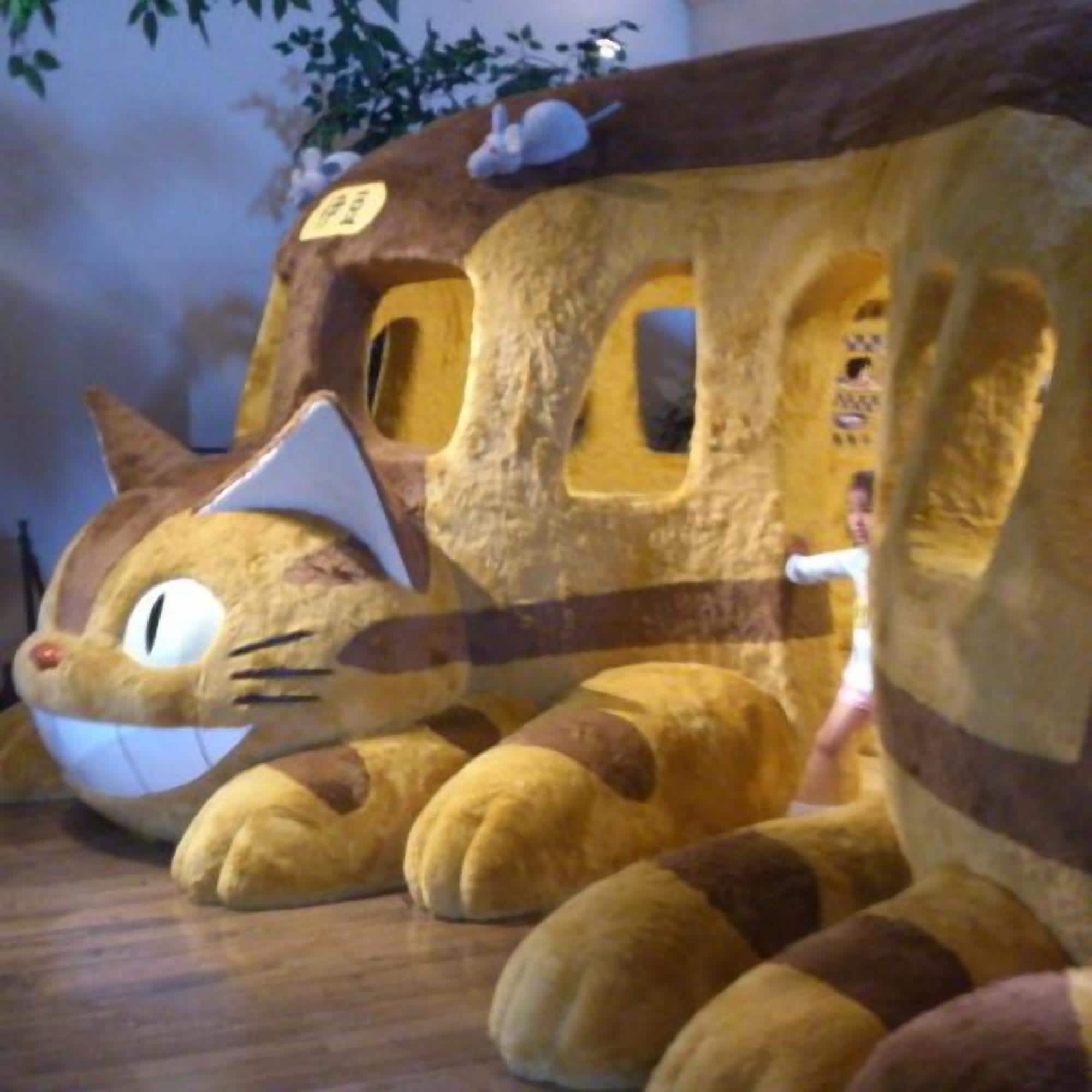 A plush toy resembling a cat with a house-like structure, possibly a toy or decoration.