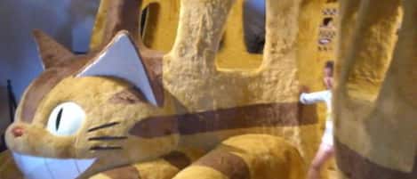 A plush toy resembling a cat with a house-like structure, possibly a toy or decoration.