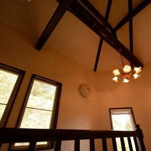 A room with a wooden ceiling beam, a hanging light fixture, and two windows. - Izukogen Hanairotei (Ito)
