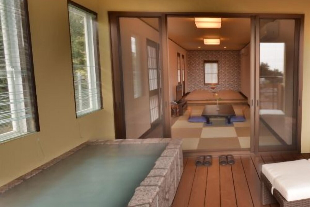 A spa room with a hot tub, wooden flooring, and a checkered floor mat.
