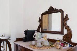 Eine Küchenarbeitsplatte mit Kaffeemaschine, Teekanne, Tassen und einem Spiegel.