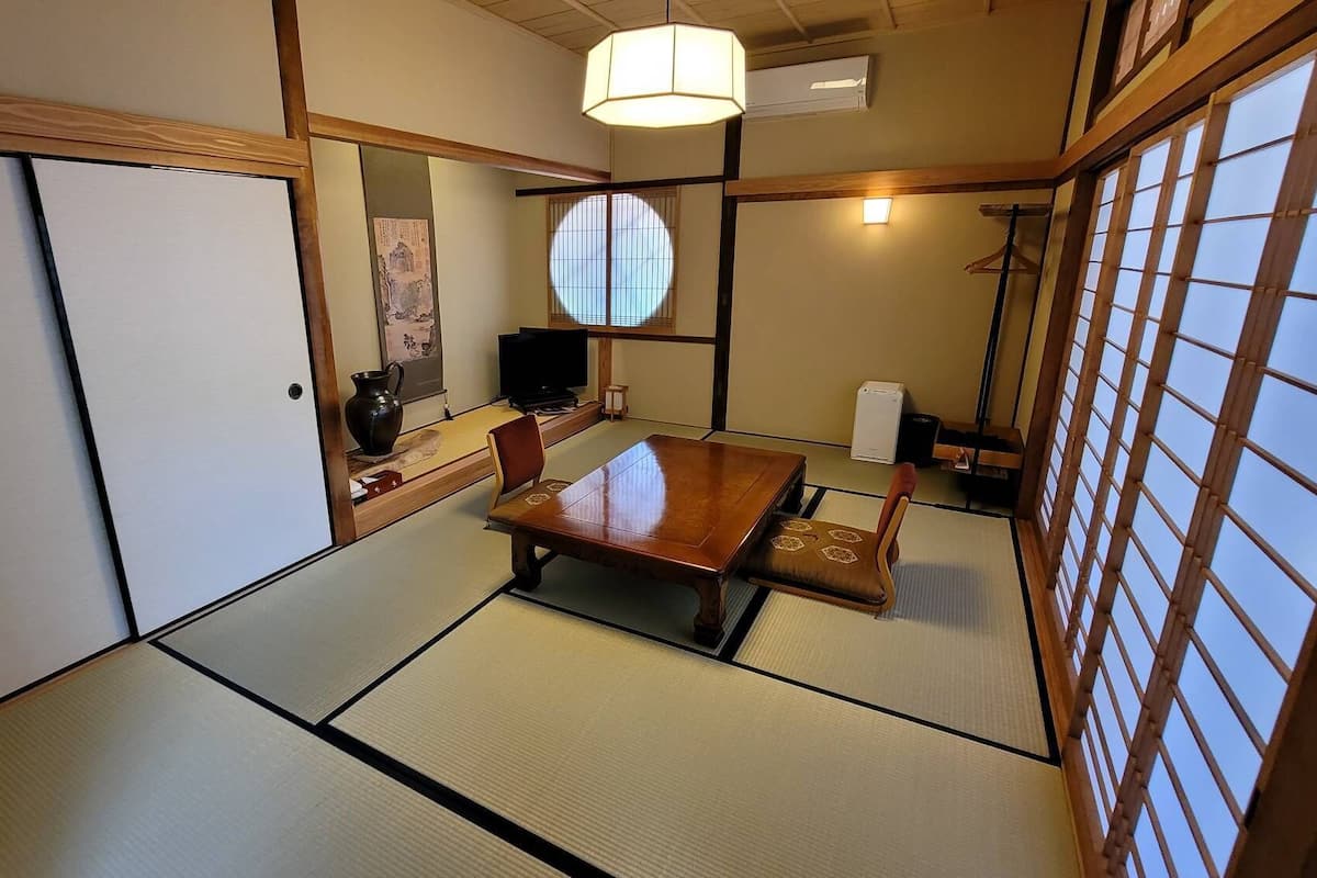 A traditional Japanese room with tatami flooring, a low table, a television, and a sliding door.