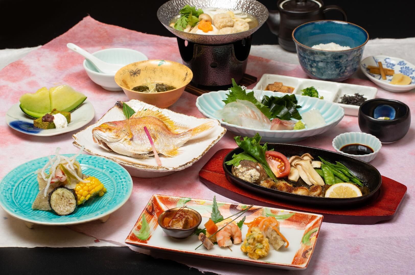 A variety of dishes on a table, including sushi, sashimi, and other Japanese cuisine.