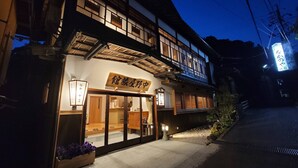 Un edificio japonés tradicional con fachada de madera, un cartel y una entrada bien iluminada.