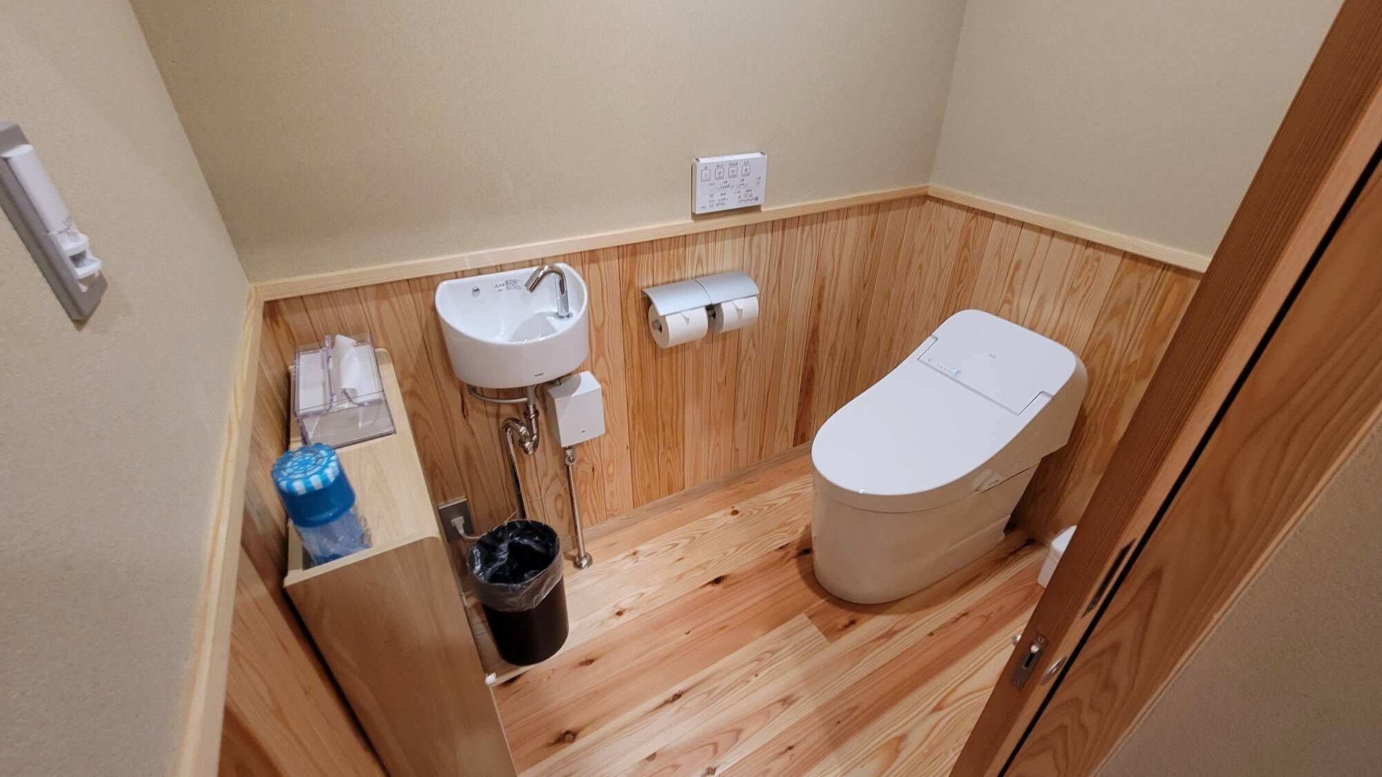 A small bathroom with a toilet, sink, and a wooden floor.