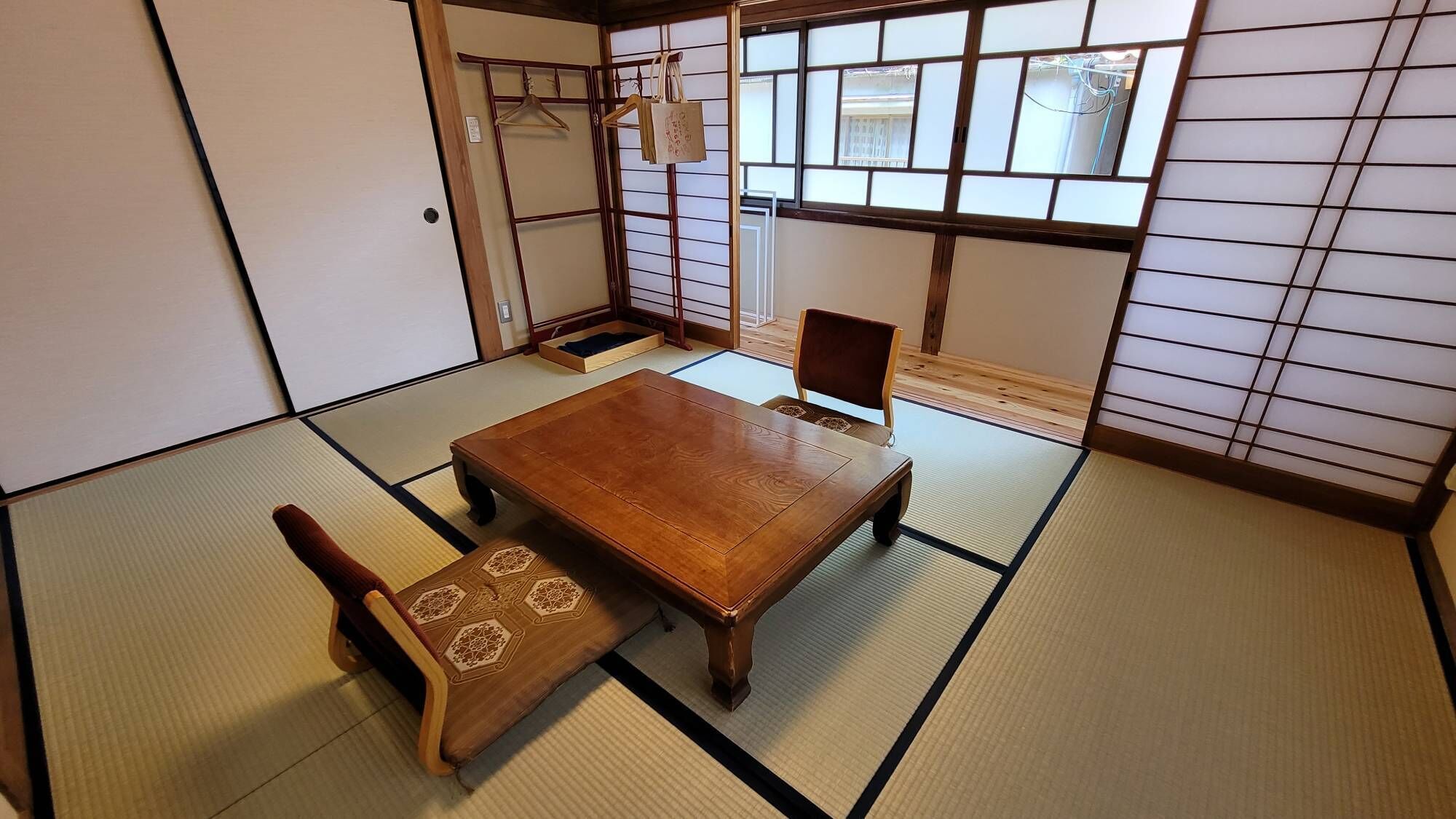 Ein traditioneller japanischer Raum mit Tatami-Bodenbelag, einem Holztisch und einem Stuhl.