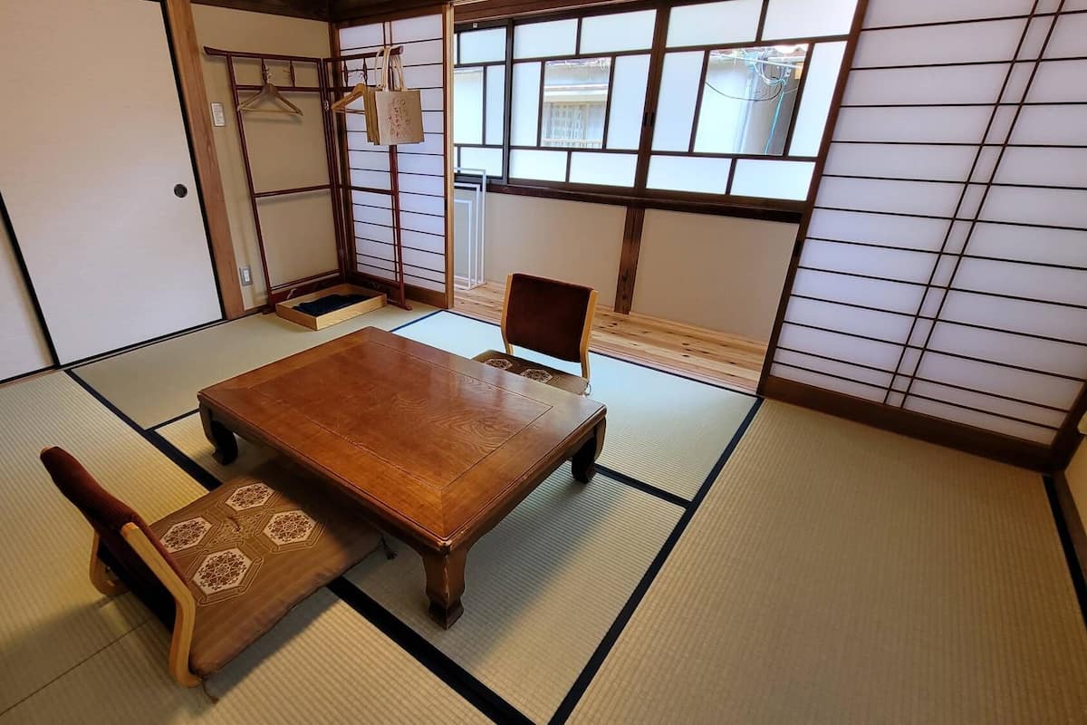 A traditional Japanese room with tatami flooring, a wooden table, and a chair.