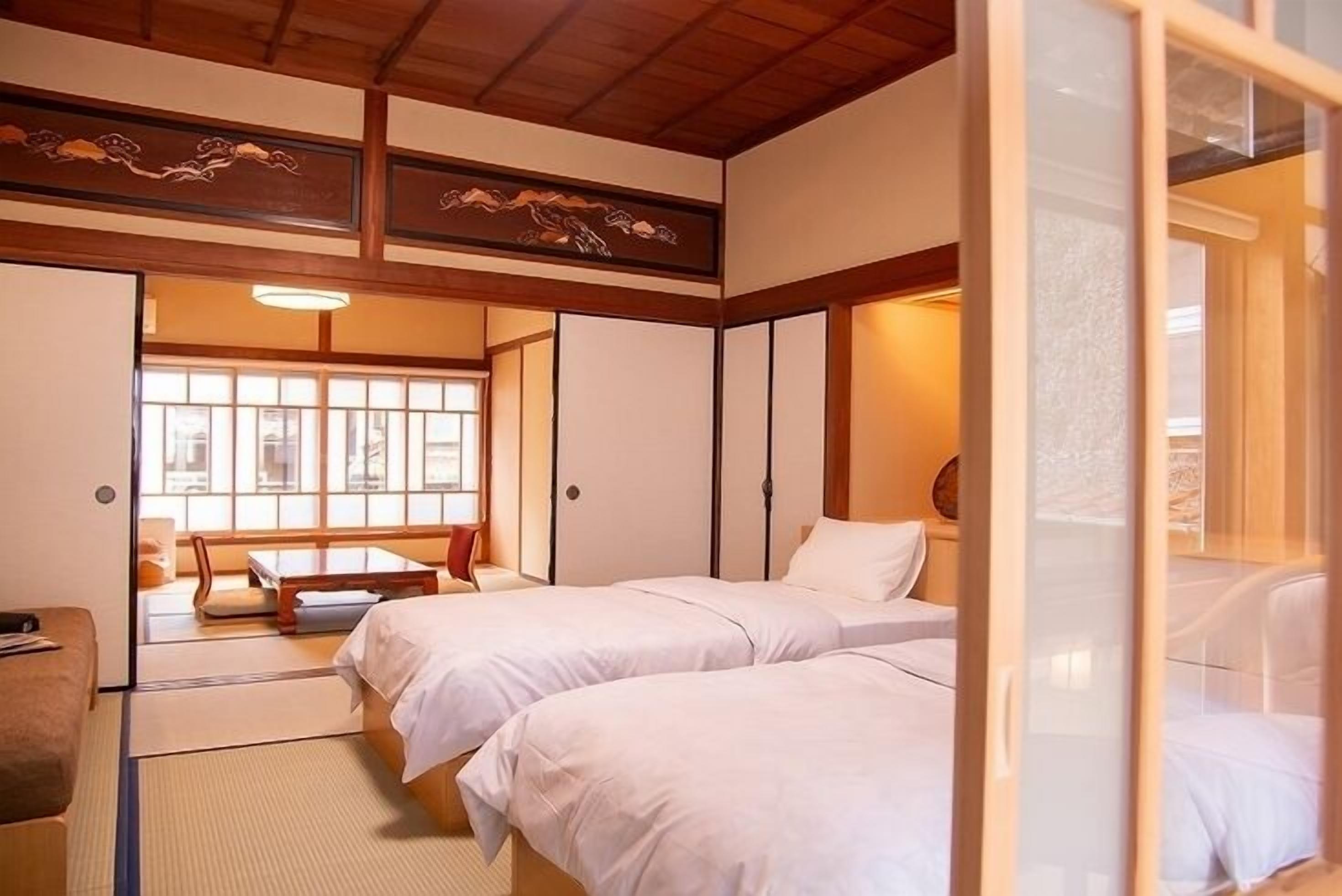 Ein traditioneller japanischer Raum mit Tatami-Boden, einer Schiebetür und einem Bett mit weißer Bettwäsche.