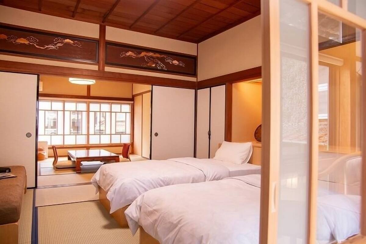 A traditional Japanese room with tatami flooring, a sliding door, and a bed with white bedding.
