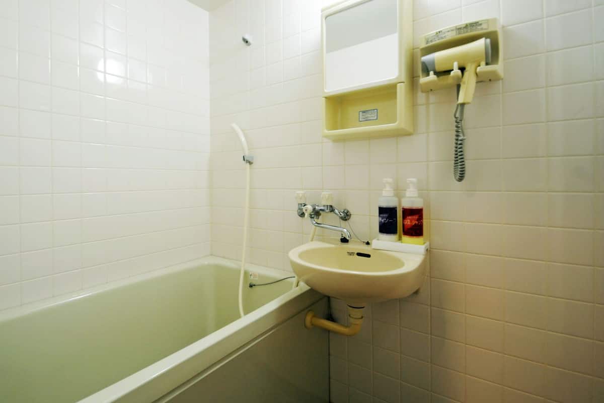 A bathroom with a bathtub, a sink, and a mirror.