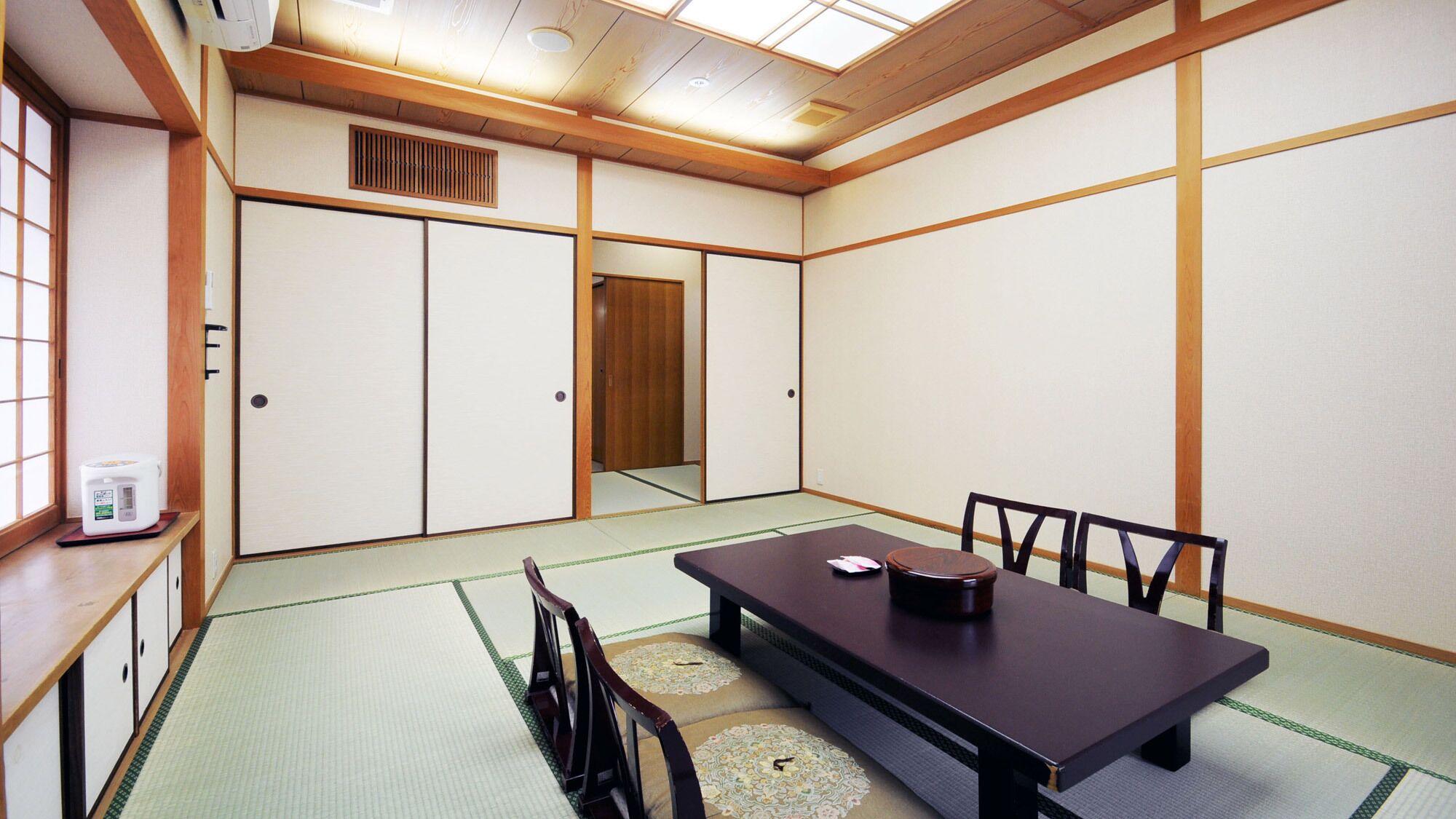 A traditional Japanese room with tatami flooring, a low table with chairs, and sliding doors.