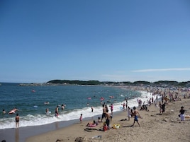 Una playa concurrida, gente nadando y caminando por la orilla.