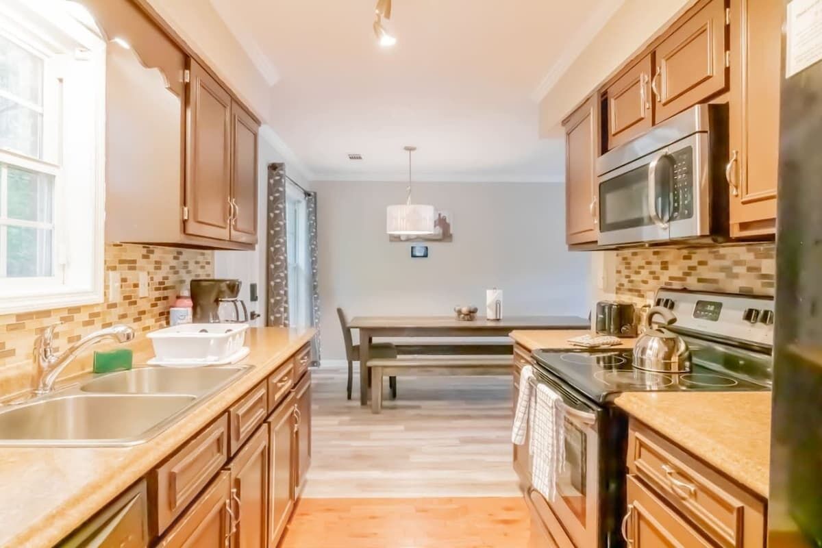 A kitchen with wooden cabinets, a stainless steel sink, a microwave, and a stove.