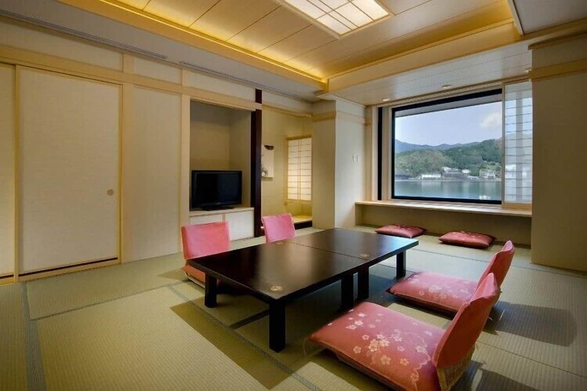 A traditional Japanese-style room with tatami flooring, a low table, and pink cushions.