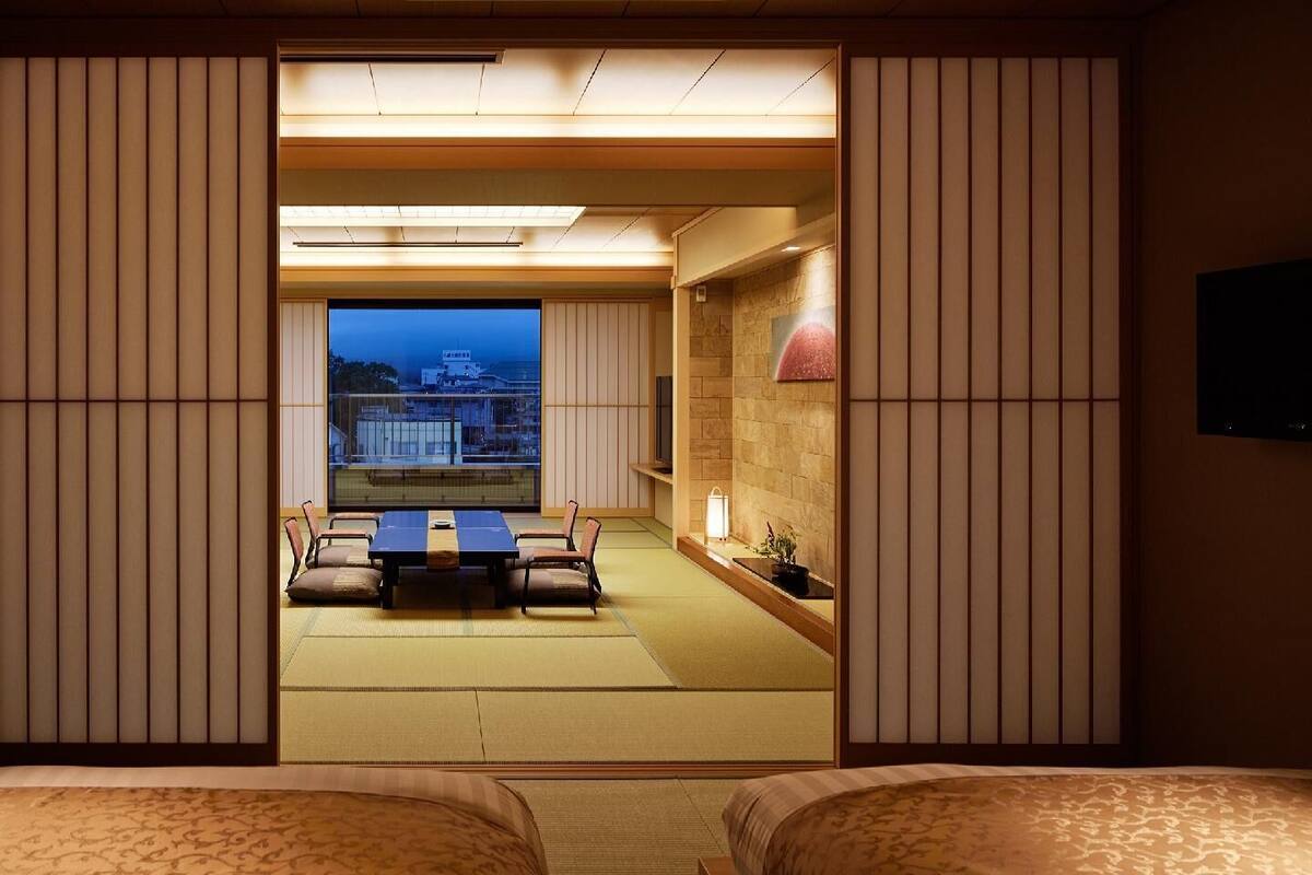 A traditional Japanese room with tatami flooring, a low table with cushions, and sliding doors.