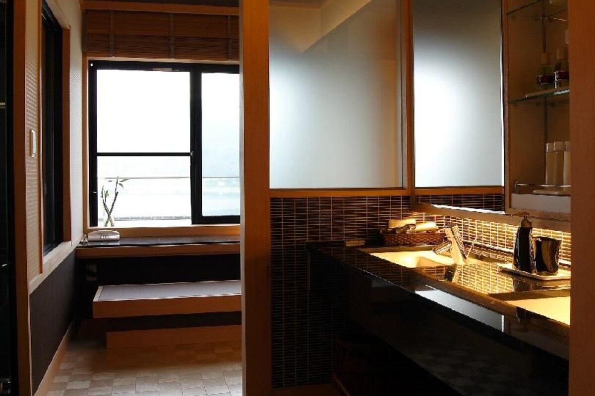 Une salle de bain avec une fenêtre, un lavabo et un miroir.