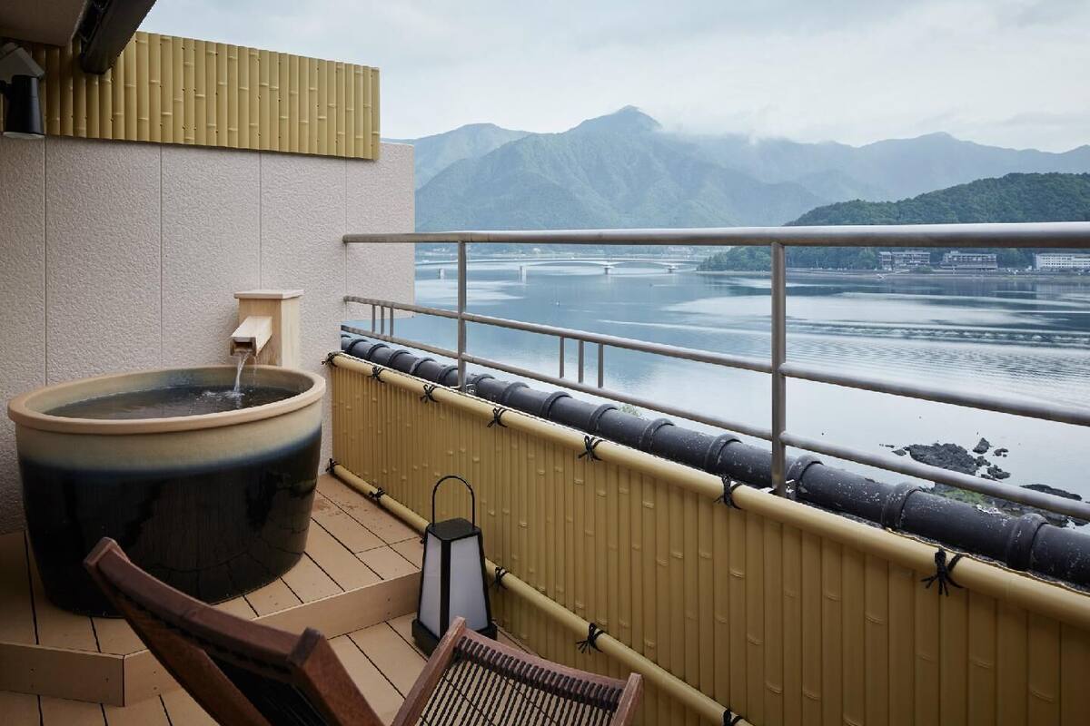 A hot tub on a balcony with a view of a lake and mountains.