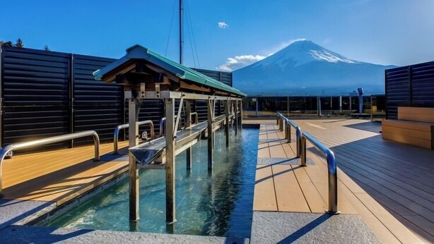 Zona de piscina con terraza de madera, barandillas metálicas y vistas a la montaña.
