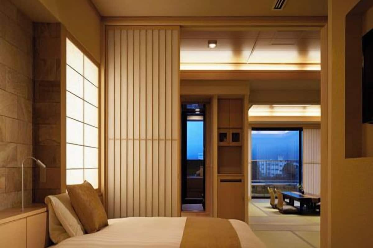 A hotel room with two beds, a view of the city, and a balcony with a table and chairs.