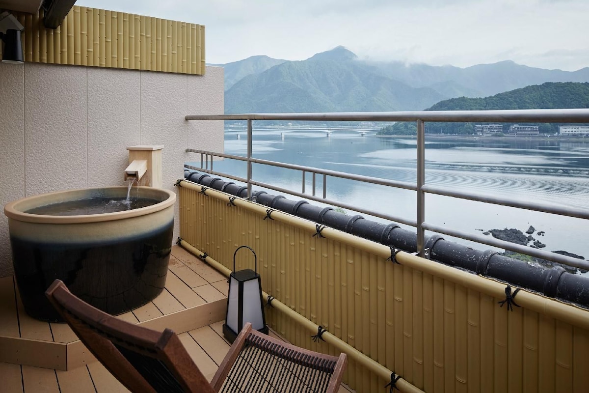 Un jacuzzi en un balcón con vistas a un lago y montañas.