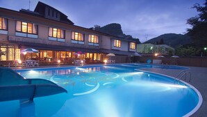 A swimming pool with a sunken design, surrounded by outdoor seating and umbrellas.