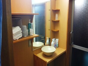 A bathroom with a sink, mirror, shelves with toiletries, and a towel rack. - Kinosaki Onsen Restaurant & Ryokan Yoshiharu (Toyooka)