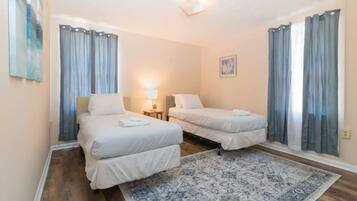 Hotellihuone, jossa on kaksi sänkyä, kuviollinen matto ja verhot.