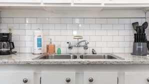 A kitchen with white cabinets, a double sink, a coffee maker, and a knife block. - Modern Interior - Delightful Doubles Unit D (Columbus)