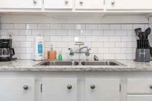 Eine Küche mit weißen Schränken, einer doppelten Spüle, einer Kaffeemaschine und einem Messerblock.