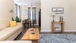A living room with a sofa, coffee table, and a 'welcome' sign. - Modern Interior - Delightful Doubles Unit D (Columbus)