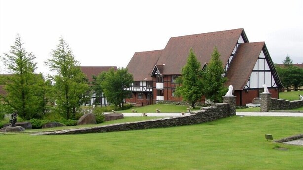 A building with a steeply pitched roof, stone walls, and a grassy lawn with statues. - Spa Pension Mary King's (Ten-ei)