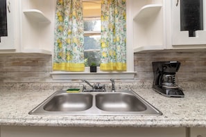 A kitchen with a double sink, a coffee maker, and a window with floral curtains. - 10 Min to Downtown, Close to Dining-Boxwood Beauty (Columbus)