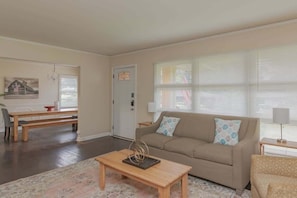 A living room with a sofa, coffee table, and a dining area with a bench and table. - 10 Min to Downtown, Close to Dining-Boxwood Beauty (Columbus)