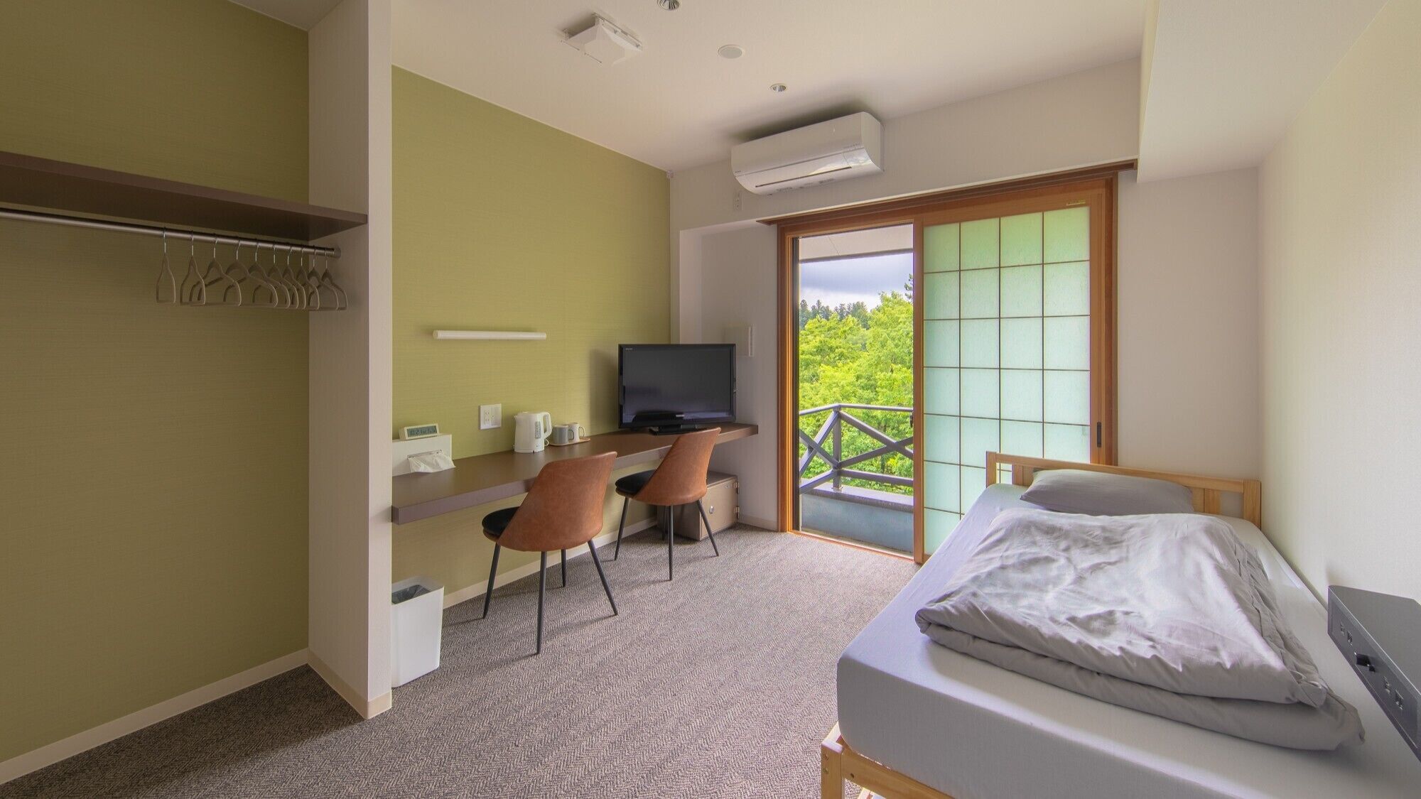 Un dormitorio con cama, un escritorio con silla, televisión y balcón con vistas.