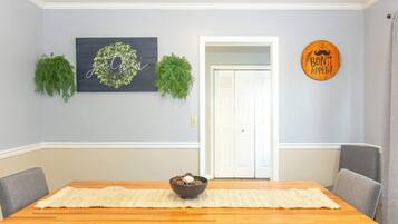 Un coin repas avec une table en bois, un bol de nourriture et un mur orné d’une inscription « Bon appétit ».