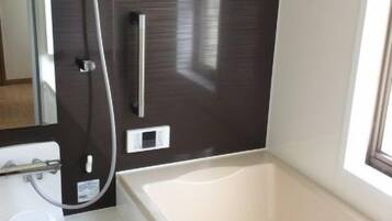 A modern bathroom with a bathtub, a shower, and a toilet.