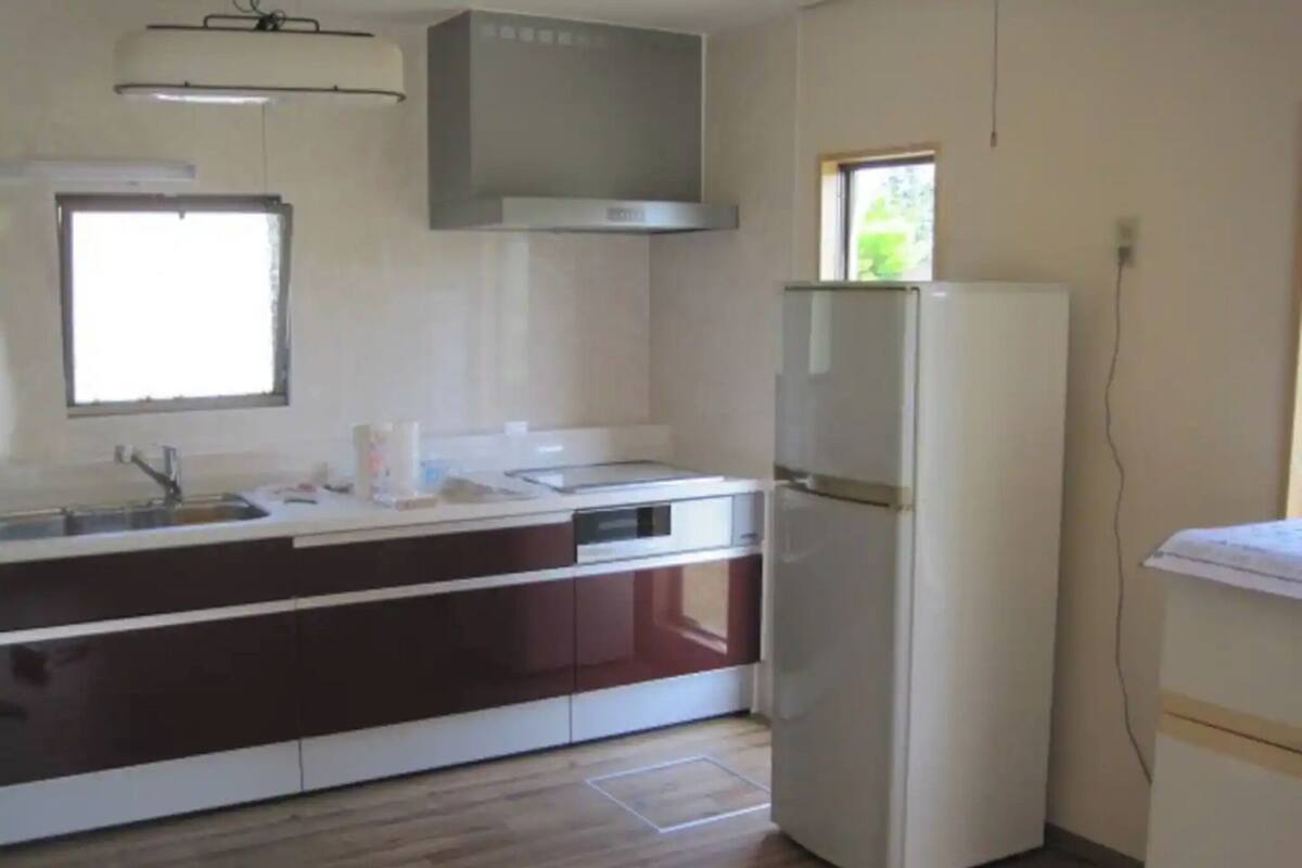 Een keuken met een witte koelkast, een spoelbak en een raam.